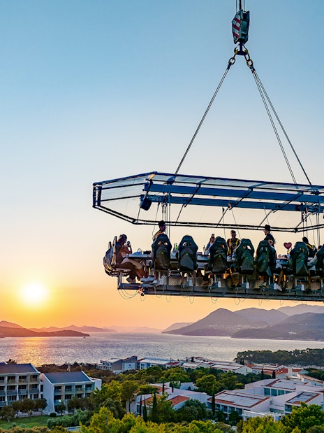 Guests dining in the sky above Dubrovnik with a sunset view of the Adriatic Sea.