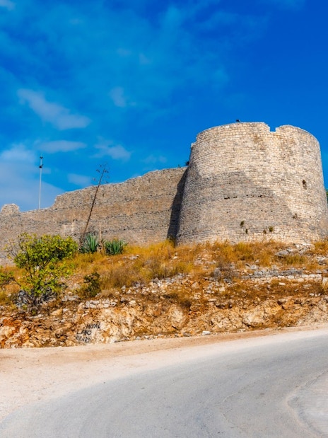 Lekuresi Castle in Sarande with stone walls and surrounding landscape.