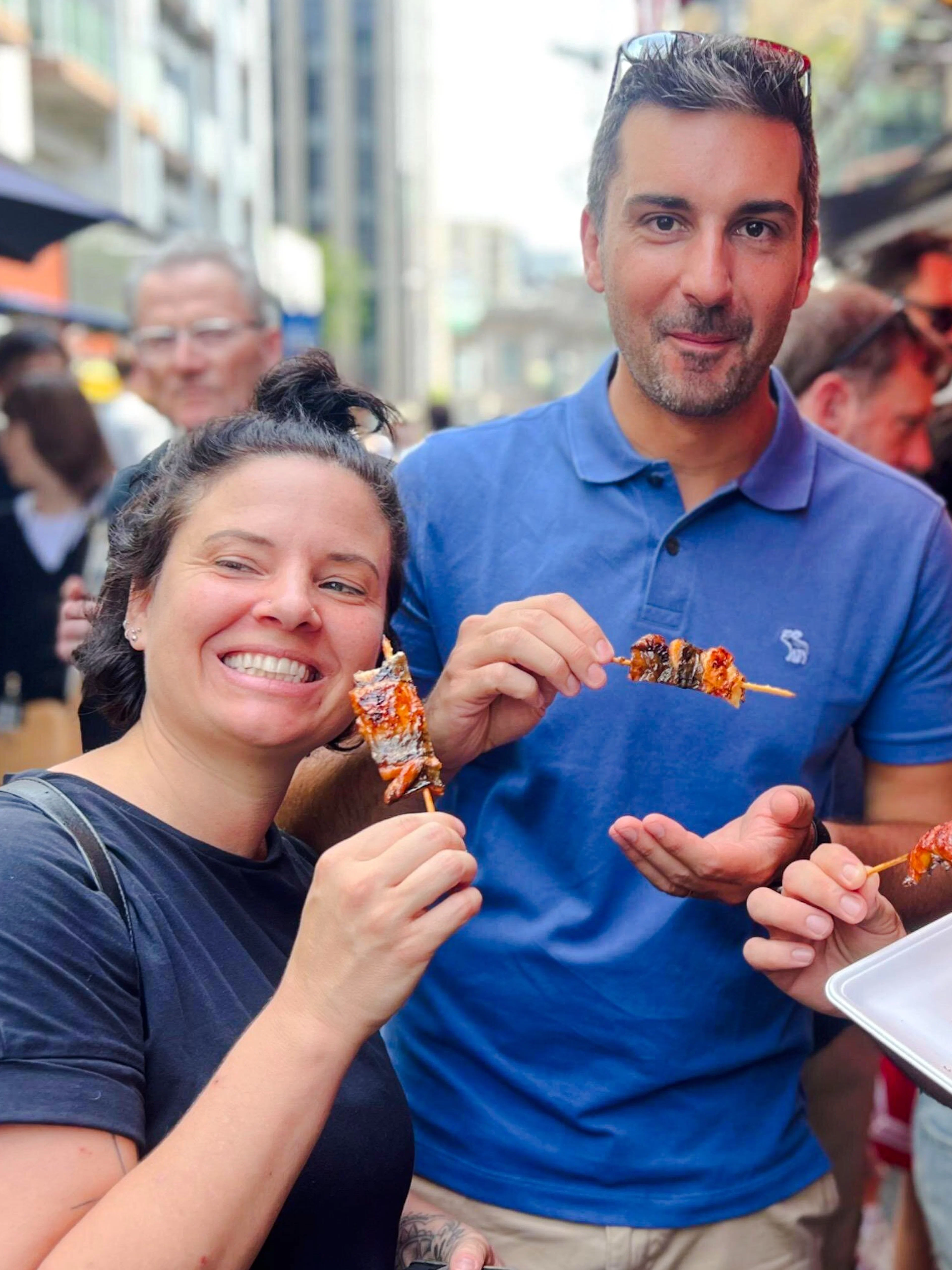 Tourists enjoying yakitori at Tsukiji Fish Market in Tokyo during a food tour.