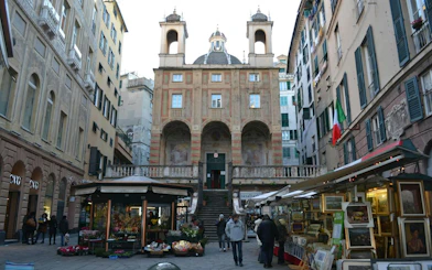 Historic building and market stalls in Genoa city center, part of the self-guided exploration game.