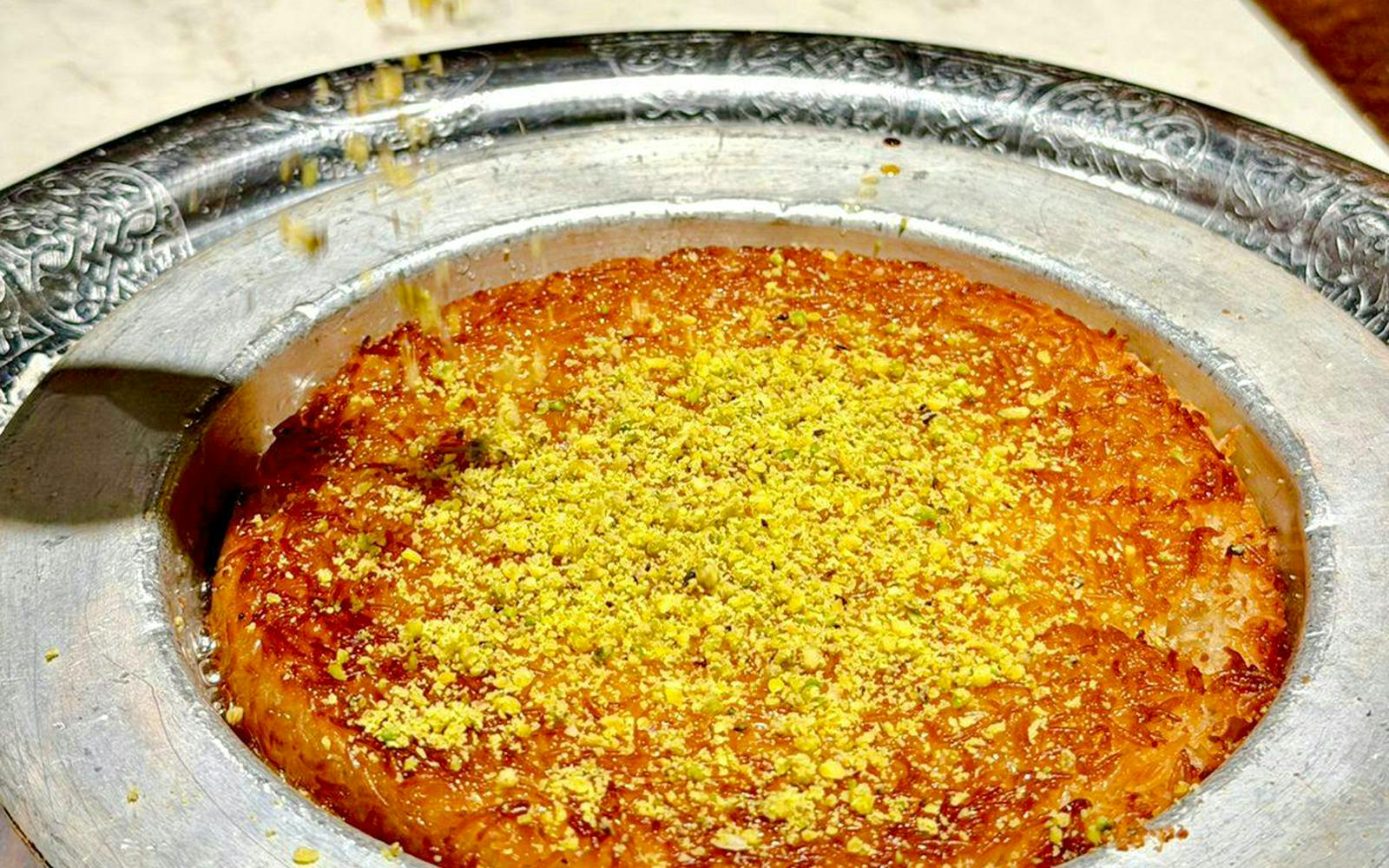 Kunafa dessert with pistachios served in a metal tray, Istanbul.