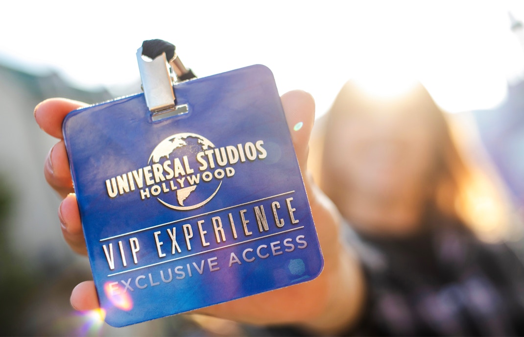 Universal Studios Hollywood entrance with iconic globe sculpture and VIP ticket holders entering.