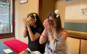 Two women participating in a traditional tea ceremony in a Kyoto tea room.