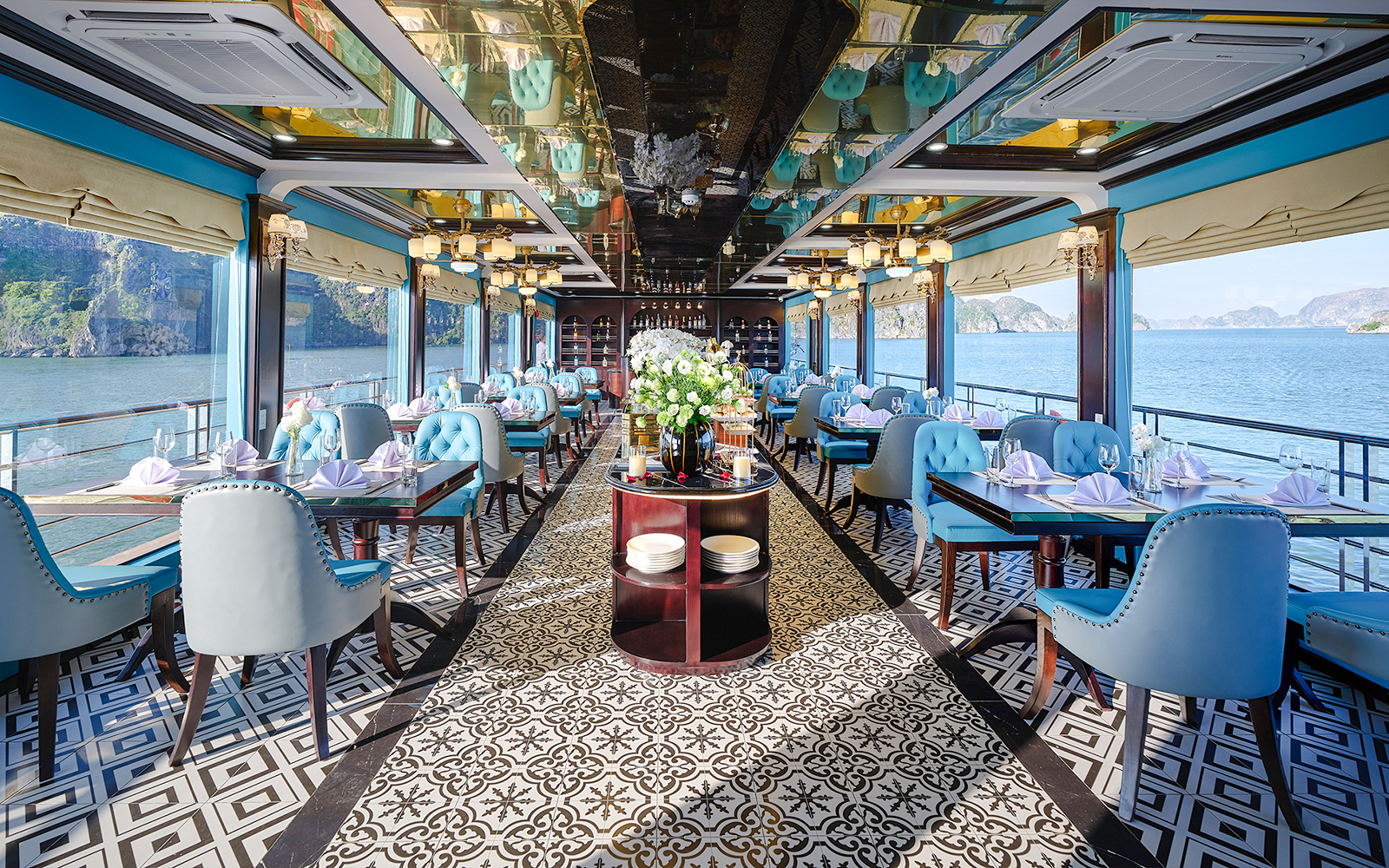 Dining room on a cruise ship with blue chairs and tables set for a meal in Ha Long Bay.