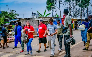 Tourists walking with a local guide in Nairobi's Kibera slum, engaging in a storytelling tour.