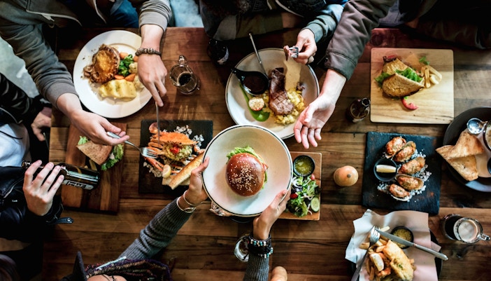 People dining at a rustic restaurant, sharing burgers and fries.