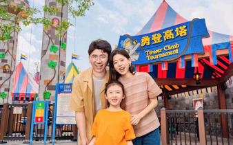 Family smiling in front of Tower Climb Tournament entrance at Legoland Shanghai.