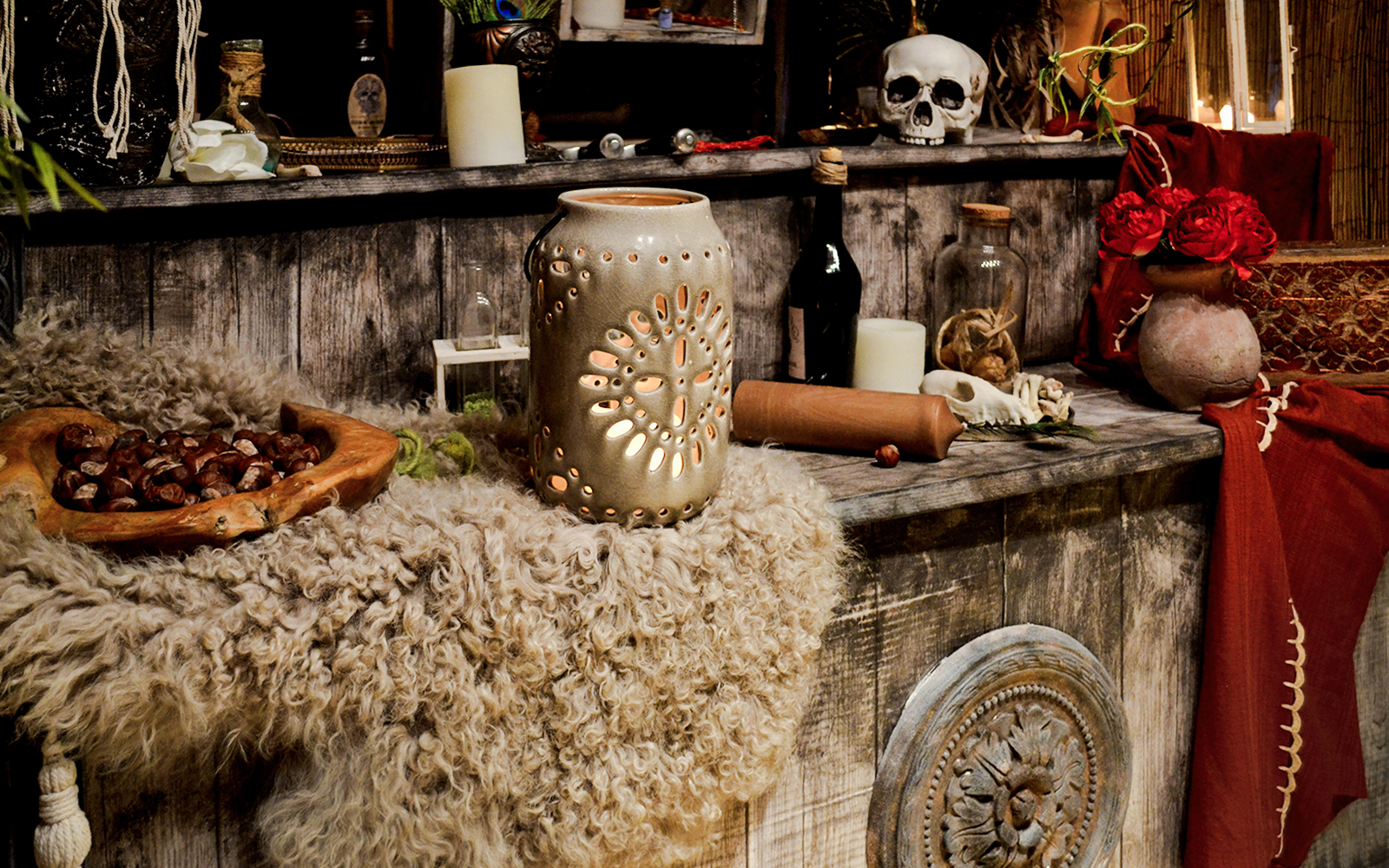 Voodoo altar with candles, skull, and ceremonial items on a wooden surface.