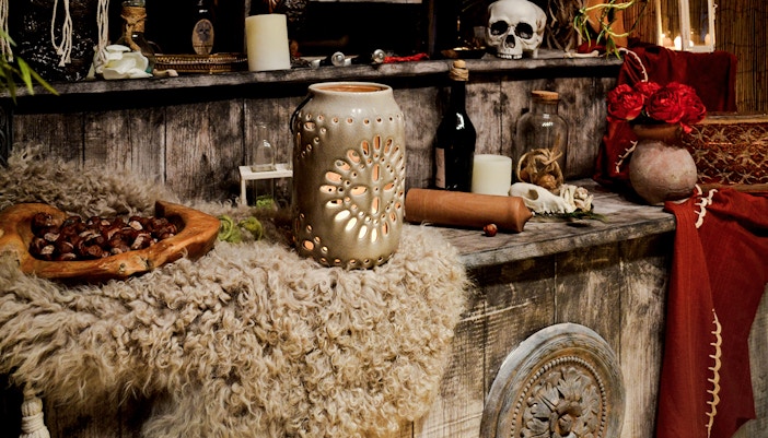 Voodoo altar with candles, skull, and ceremonial items on a wooden surface.