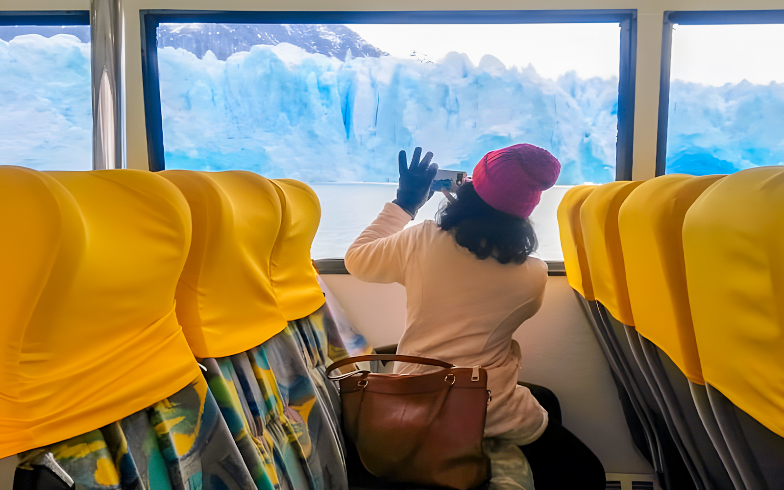 Tourist photographing Perito Moreno Glacier from boat interior, Argentina.
