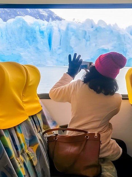 Tourist photographing Perito Moreno Glacier from boat interior, Argentina.