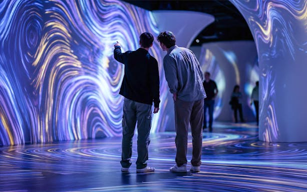 Visitors observing digital vibrant projections on museum walls and floor.