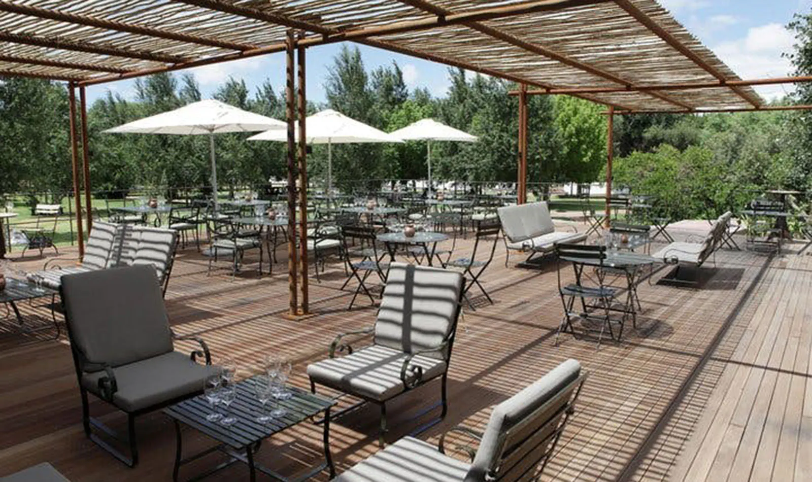 Outdoor seating area at a Cape Town vineyard with tables and chairs under a pergola.