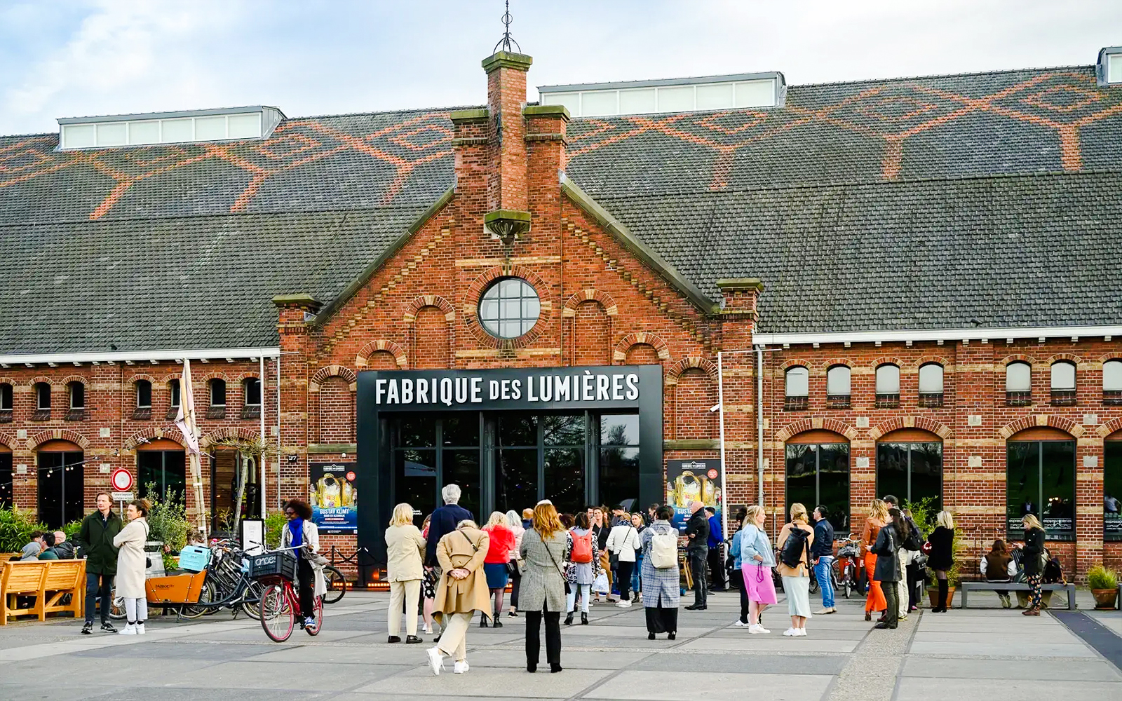 Visitors outside Fabrique des Lumières, a cultural venue in a historic brick building.