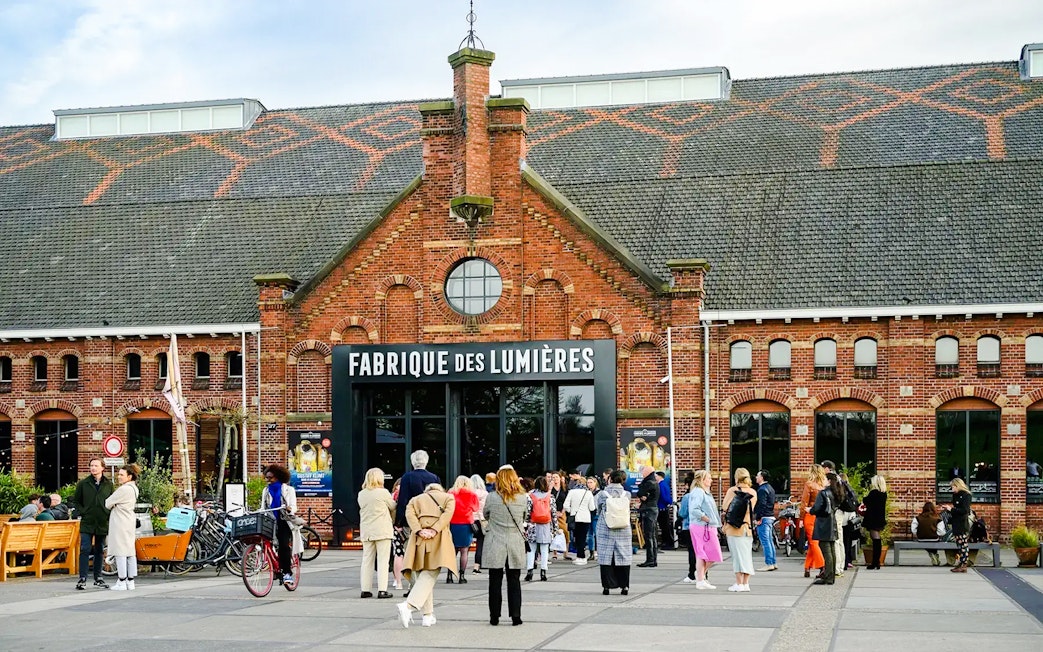 Visitors outside Fabrique des Lumières, a cultural venue in a historic brick building.