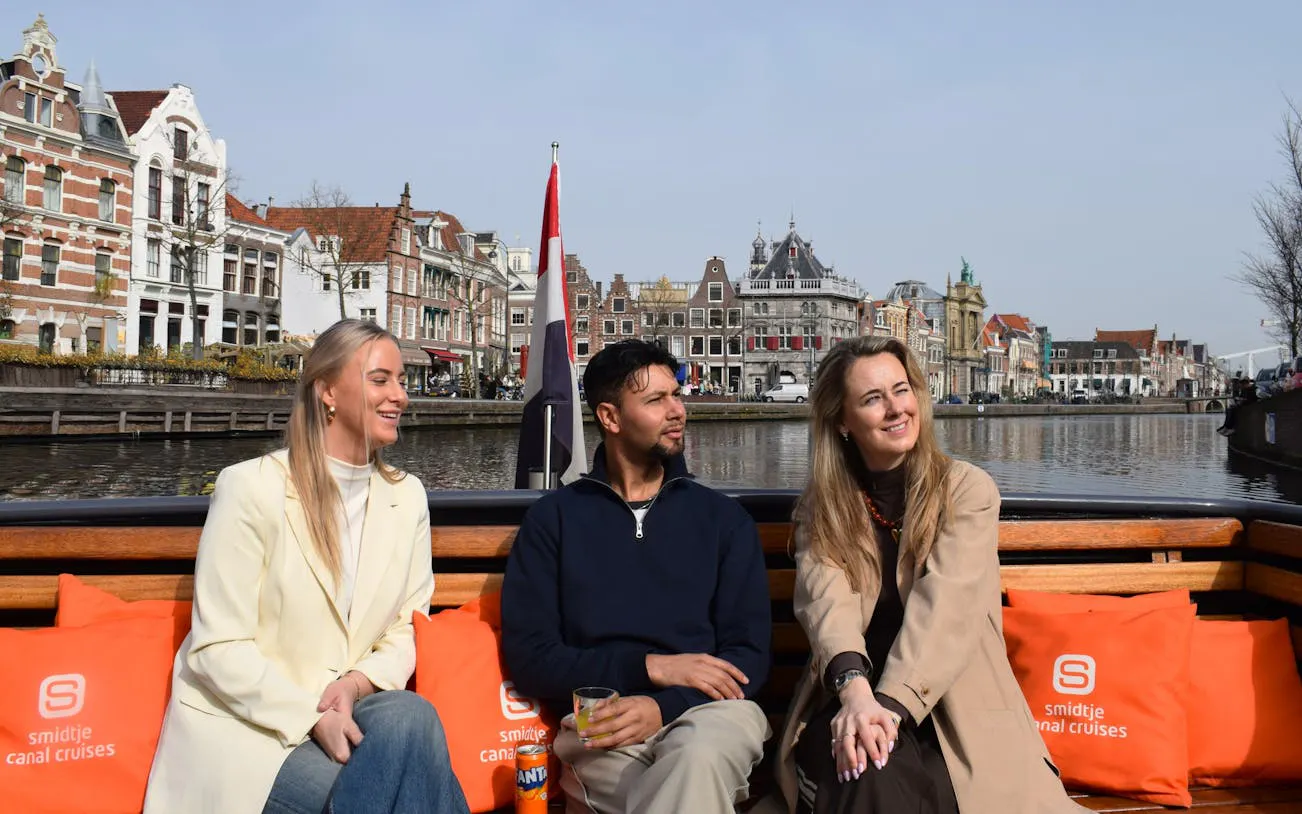 Haarlem canal cruise with people enjoying views of historical buildings along the water.