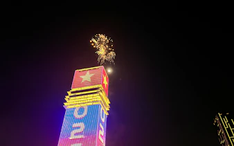 Fireworks above a lit skyscraper in Ho Chi Minh City during New Year’s Eve cruise.