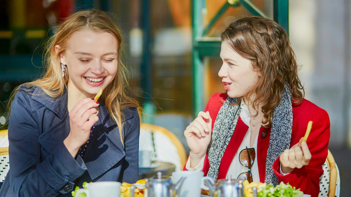 Two young women enjoying lunch at a Parisian outdoor cafe.