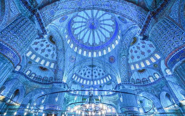 Interior view of the Blue Mosque's ornate dome and intricate tilework in Istanbul, Turkey.