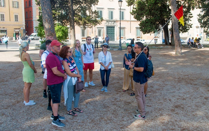 Tour group in Rome listening to a guide near historical buildings.