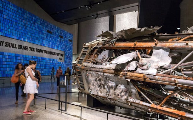 Wreckage display at 9/11 Memorial Museum, New York, with visitors observing exhibits.