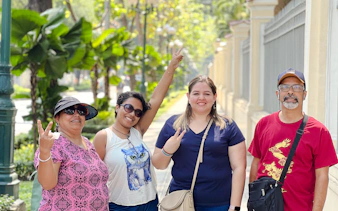 Group enjoying a walking tour in Saigon, Ho Chi Minh City, with lush greenery and historic architecture.