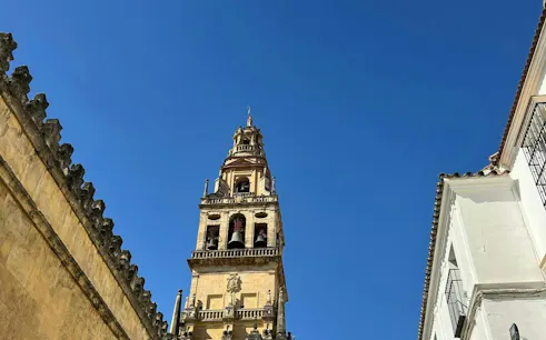 Bell tower of the Mosque-Cathedral in Córdoba under a clear blue sky.