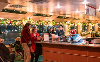 Guests enjoying drinks at a decorated bar on the Circle Line Harbor Lights Cruise.