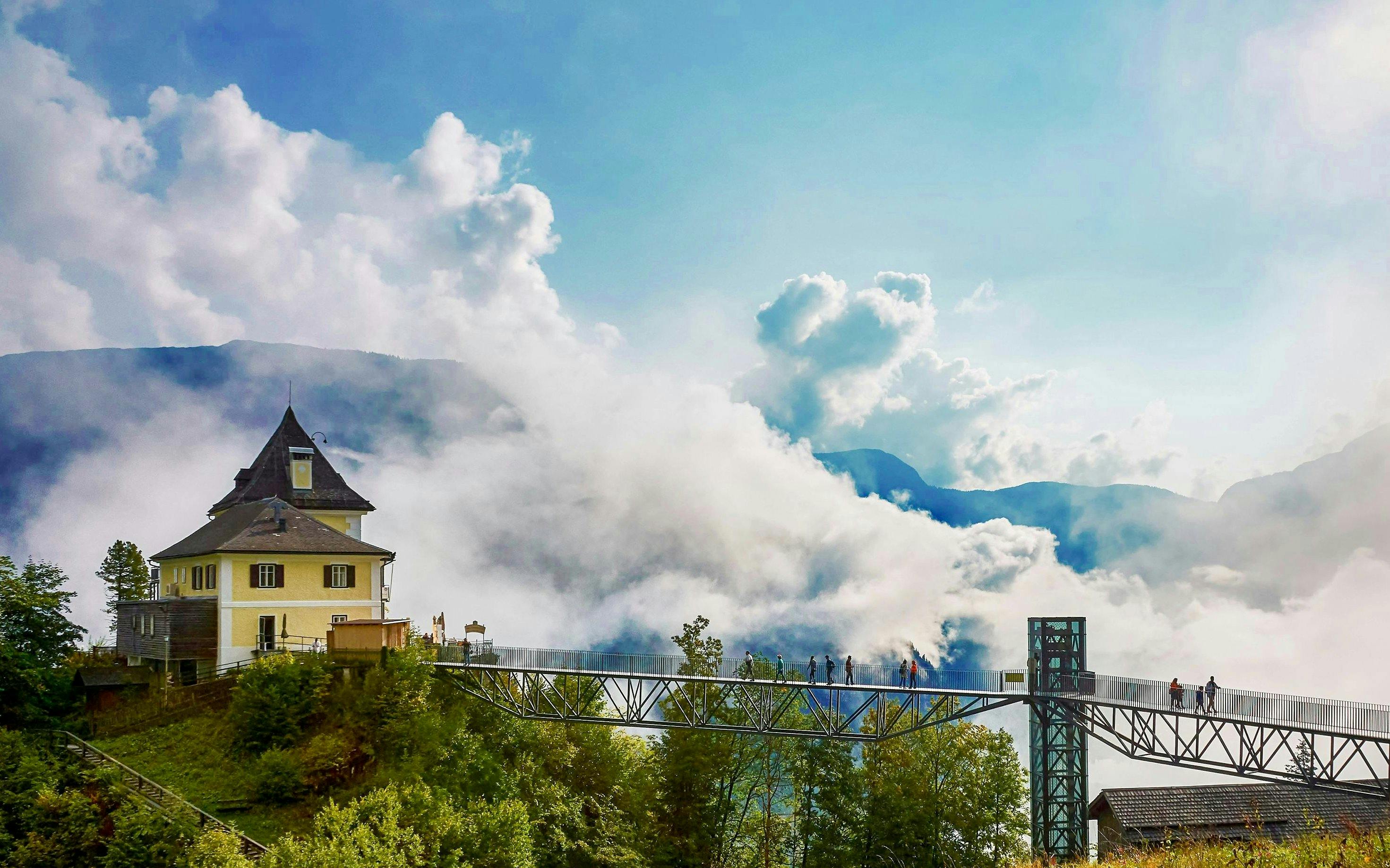 Scenic view of Hallstatt Skywalk with visitors, surrounded by clouds and mountains, near Vienna.