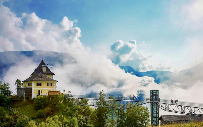 Scenic view of Hallstatt Skywalk with visitors, surrounded by clouds and mountains, near Vienna.