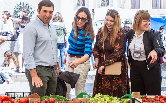 Tourists exploring fresh produce at Campo de' Fiori market during a guided street food tour.