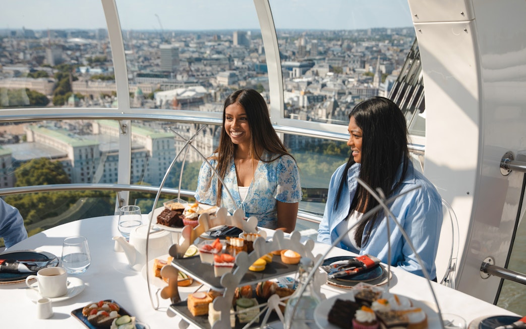 London Eye capsule with people enjoying afternoon tea and city view.