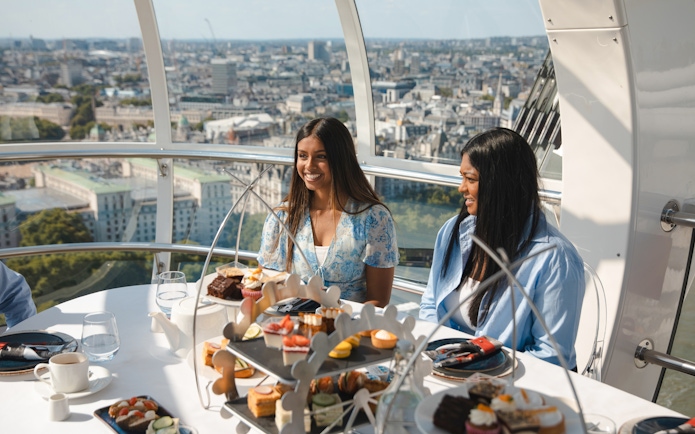 London Eye capsule with people enjoying afternoon tea and city view.