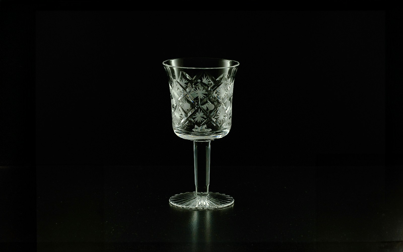 Intricately designed crystal wine glass on a dark background.
