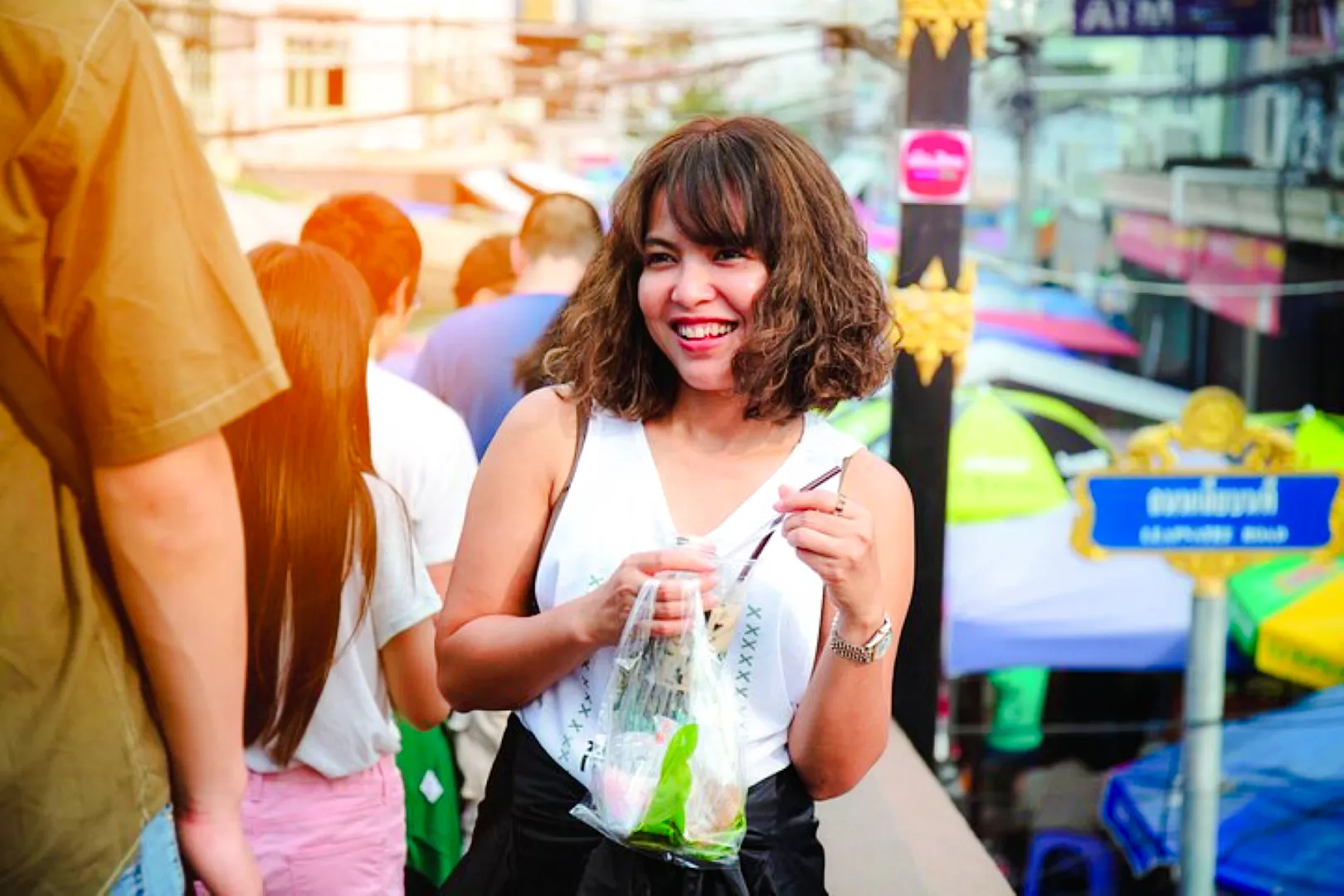 Smiling visitor enjoying street food at Amphawa Floating Markets during a private tour from Laem Chabang, Pattaya.