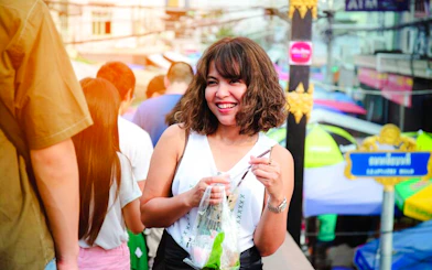 Smiling visitor enjoying street food at Amphawa Floating Markets during a private tour from Laem Chabang, Pattaya.