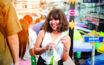 Smiling visitor enjoying street food at Amphawa Floating Markets during a private tour from Laem Chabang, Pattaya.