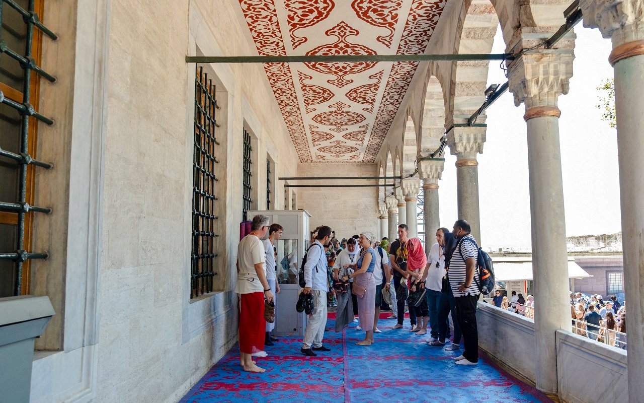 Visitors on a guided tour inside Hagia Sophia, Istanbul, standing on a decorated corridor.
