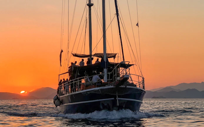 Sunset cruise on Athens Riviera with passengers enjoying wine and snacks.