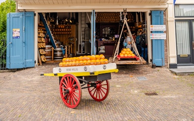 Edam cheese wheels on a cart outside a historic market in Edam, Netherlands.