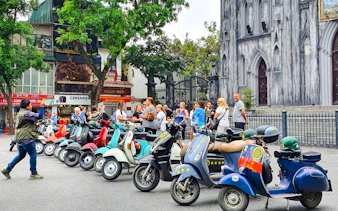 Tourists gather near Vespas in front of St. Joseph's Cathedral, Hanoi, for a photo tour.
