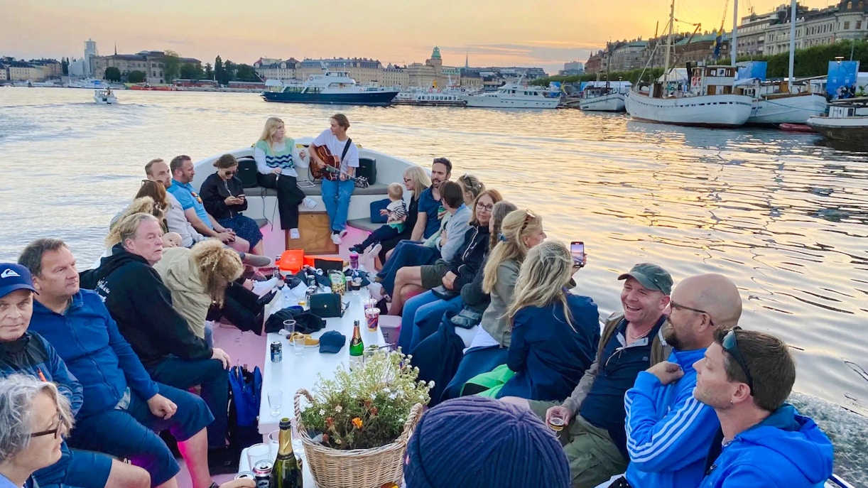 Sightseeing boat tour with people enjoying a sunset view in Stockholm.