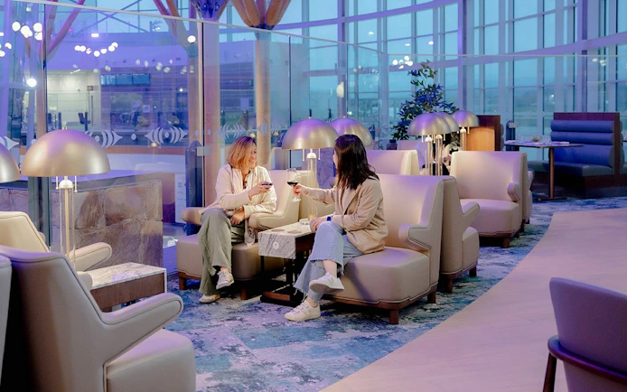 Two people enjoying drinks at Plaza Premium First lounge, Vancouver International Airport.