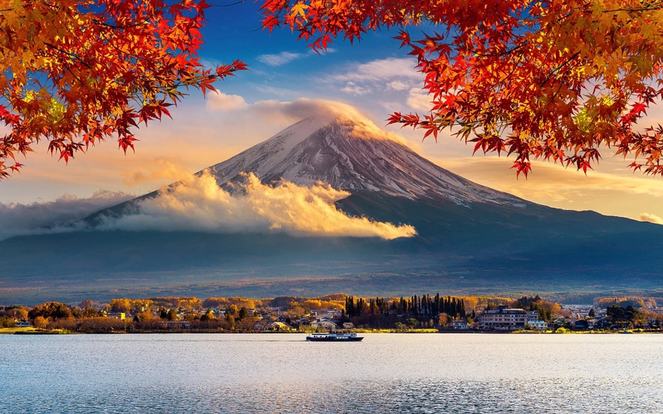 Mount Fuji with autumn leaves and a boat on the lake in Japan.