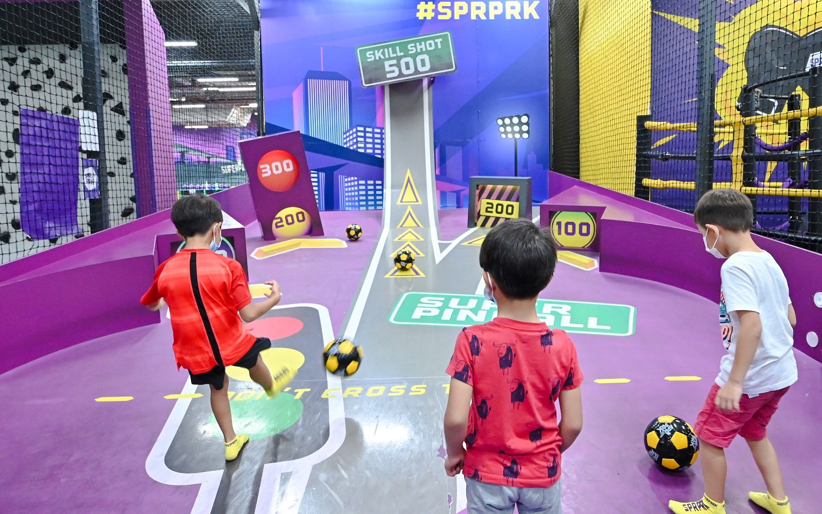 Children playing football at SuperPark Singapore's skill shot area.