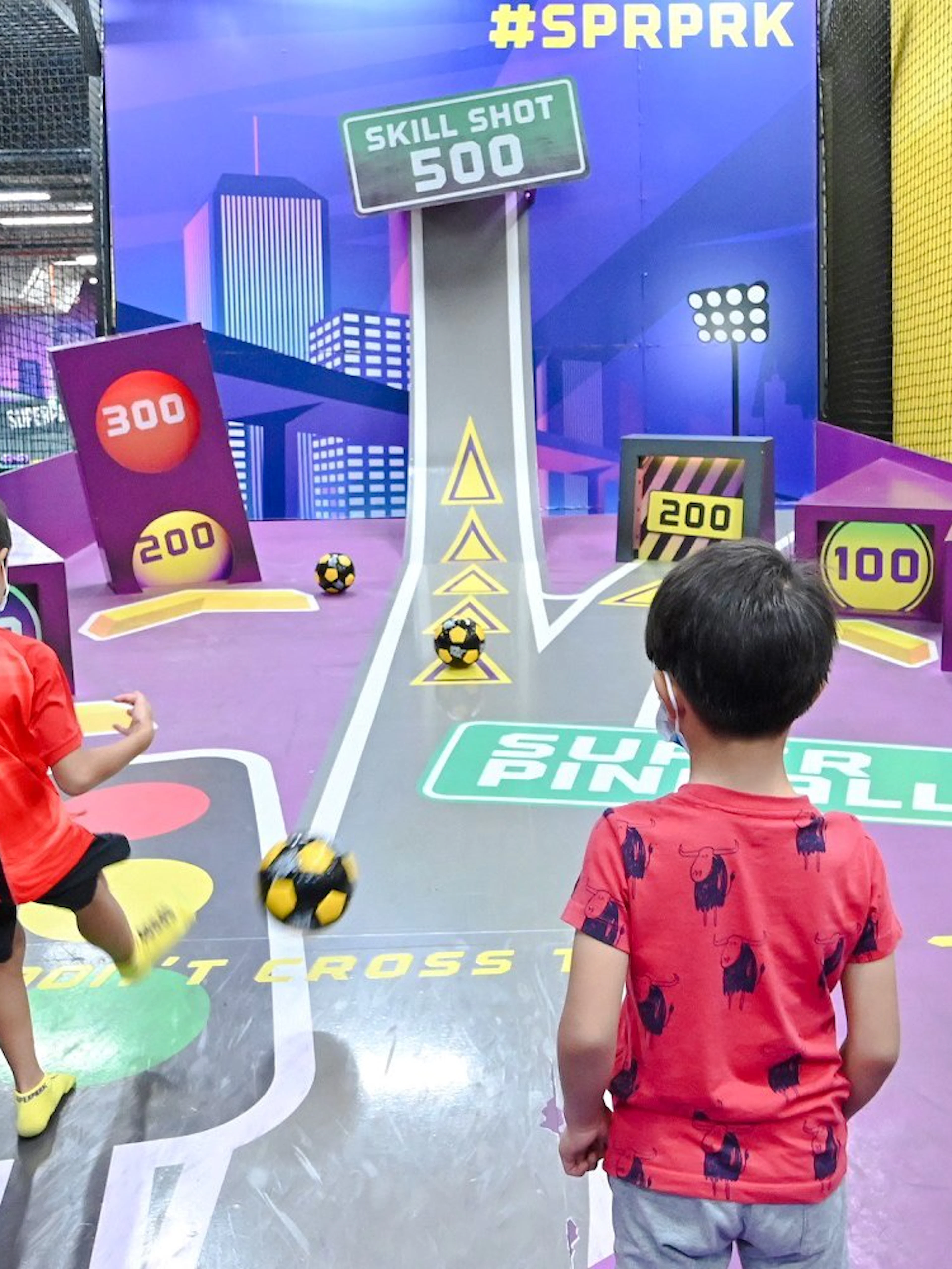 Children playing football at SuperPark Singapore's skill shot area.