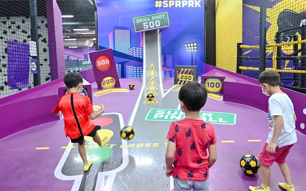 Children playing football at SuperPark Singapore's skill shot area.