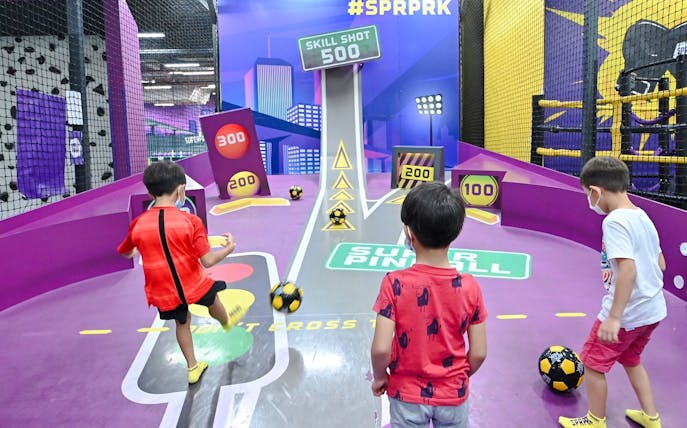 Children playing football at SuperPark Singapore's skill shot area.