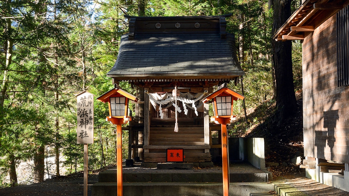Arakura Sengen Shrine small wooden structure with lanterns in forest setting.