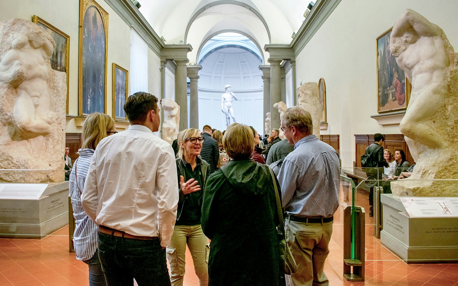 Tour guide talking to group with the statue of Michaelangelo's David in the background at the Accademia Gallery